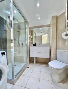 a bathroom with a shower and a toilet and a sink at Elegant Hyde Park View Retreat With Gym & Rooftop Pool in Sydney