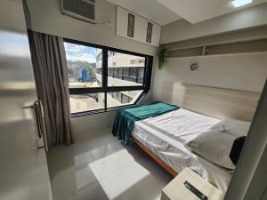 a small bedroom with a bed and a large window at @ondinaapartreservas Pé na Areia 441 in Salvador