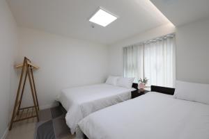 twee bedden in een kamer met een raam en een statief bij AweStay in Goyang +120 foto's