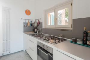 eine weiße Küche mit Herd und Spüle in der Unterkunft "Ulivi House" inside a Private Park, shared Pool, Tennis, 2 AC BDR, 2BTH, parking next home and private garage in Lerici! in Lerici