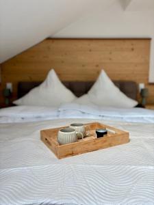 a wooden tray with bowls on top of a bed at ALLGÄUHERZ - Ferienwohnung zentral in Nesselwang - inklusive KÖNIGSKARTE in Nesselwang +10 photos