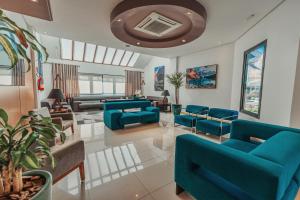 a living room with blue chairs and a couch at Hotel Laghetto Viale in Gramado
