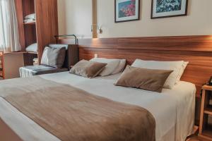 a bedroom with a large bed with a wooden headboard at Hotel Laghetto Viale in Gramado