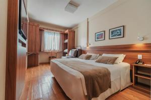 a hotel room with a large bed and a television at Hotel Laghetto Viale in Gramado