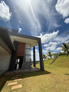 a house with a glass door on a grass field at Sítio em Jequitibá Vista Incrível Próximo a Sete Lagoas in Jequitibá
