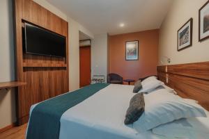 a bedroom with a large bed with a flat screen tv at Hotel Laghetto Viale in Gramado