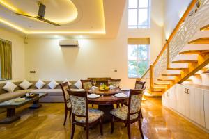 a dining room with a table and chairs and a couch at Alaya Stays Ramgarh Colonial-Style 2-BHK Villa Amidst the Hills with Private Pool & Garden in Jamwa Rāmgarh