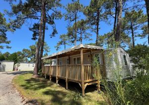 a cabin in the woods with a porch and trees at Bungalows Cap-Ferret - BandB La conciergerie in Lège-Cap-Ferret