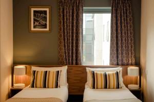 duas camas em um quarto de hotel com janela em DCU Rooms em Dublin