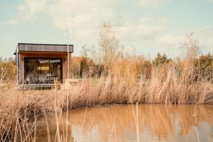 a small building next to a body of water at Le Piloti in Saint-Quentin-en-Tourmont +18 photos