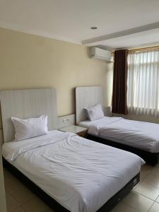una camera d'albergo con due letti e una finestra di tekMIRA Hotel a Bandung