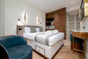 a bedroom with a large white bed and a blue chair at GuestReady - The Fitzroy Hotel in London