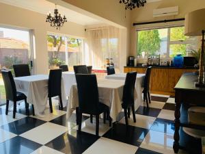 a dining room with a white table and black chairs at His Oath Guesthouse in Potchefstroom
