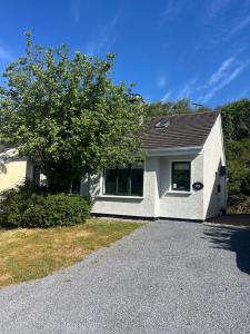 a white house with a tree in front of it at 112 Clifden Glen in Clifden