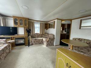 a living room with couches a table and a tv at Guest house PURINI in Jūrmala