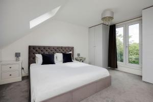 Un dormitorio blanco con una cama grande y una ventana. en Veeve - The Garden Home, en Londres