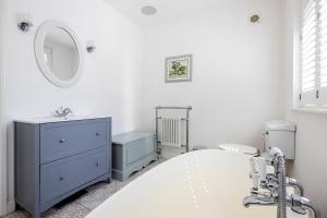 Un dormitorio blanco con una cómoda azul y un espejo. en Veeve - The Garden Home, en Londres 20 fotos más