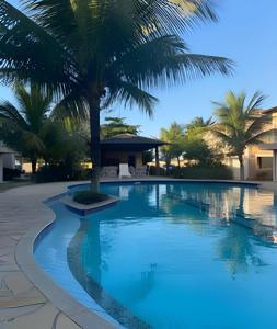 a swimming pool with a palm tree in the middle at Adorável Casa em Cond. de frente para a Praia Rasa in Búzios
