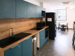 een keuken met blauwe kasten en een zwarte koelkast bij Auberge de jeunesse HI Clermont-Ferrand in Clermont-Ferrand +17 foto's