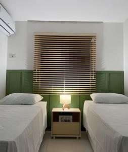 a bedroom with two beds and a table with a lamp at Adorável Casa em Cond. de frente para a Praia Rasa in Búzios