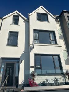 a white building with black windows at Causeway Bay Guesthouse Portrush in Portrush