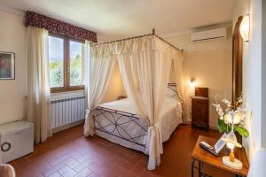 a bedroom with a canopy bed and a window at Bio Agriturismo I Lapi in Catabbio