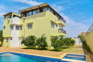 a yellow house with a swimming pool in front of it at RELAX RESIDENCES Aéroport AIBD in Toulé