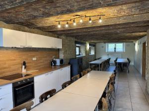 a kitchen with white cabinets and tables and chairs at Gîte La Bavière in Chassepierre
