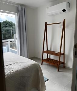 a white bedroom with a bed and a window at Casa de 2 suites com piscina e churrasqueira in Armacao dos Buzios