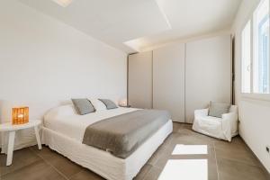 a white bedroom with a bed and a chair at Villa Elisa 