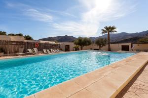 a swimming pool with chairs and mountains in the background at Cortijo El Sotillo in San José