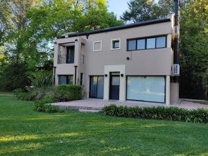a white house with a lot of windows at Casa Quinta en Barrio Cerrado Los Cardales in Campana