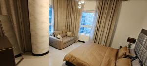 a bedroom with a bed and a chair and a window at JLT 1BR Marina Skyline View in Dubai