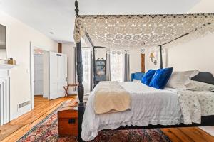 a bedroom with a canopy bed with blue pillows at Historic Waterfront Home and Cottage in Groton