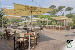 ein Restaurant mit Tischen und Sonnenschirmen auf einer Terrasse in der Unterkunft HOTIDAY Room Collection - Milano Marittima in Milano Marittima