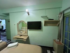 a room with a bed with a mirror and a tv at KISABEL Budget Hotel in Tanah Rata