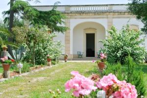 um jardim com flores cor-de-rosa em frente a uma casa em Agriturismo Villa Coluccia em Martano