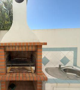 a brick pizza oven sitting next to a sink at CASA DIAS RAPOSO by Stay in Alentejo in Vila Nova de Milfontes
