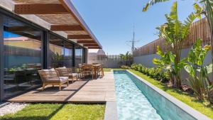 un patio trasero con terraza de madera y piscina en Stunning Beach House with Pool by LovelyStay, en Santo Isidoro