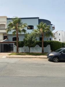 a car parked in front of a building with palm trees at Maison D hôtes Aboulanwar in El Jadida