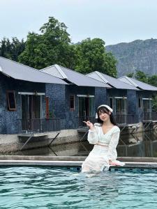 eine Frau sitzt im Wasser vor einem Haus in der Unterkunft Trang an rice field homestay in Ninh Bình