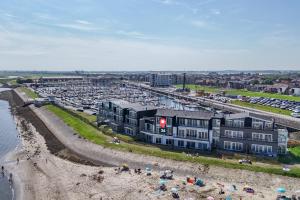 a building on the beach next to a parking lot at Vakantiewoning aan het water 'Oester Oase' - met 2 balkons - Vista Maris - Nr 36 in Sint Annaland