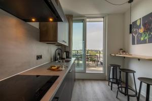 a kitchen with a counter with stools and a window at Vakantiewoning aan het water 'Oester Oase' - met 2 balkons - Vista Maris - Nr 36 in Sint Annaland