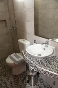 a bathroom with a sink and a toilet and a mirror at Evanthia Toroz Rooms & Studios in Mithymna