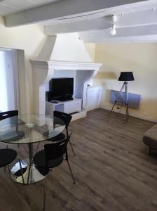 a living room with a glass table and a television at Les petits volets bleus in Bouchet