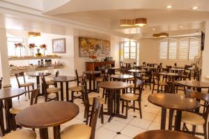 a restaurant with tables and chairs in a room at Colonial Palace Hotel in Pará de Minas