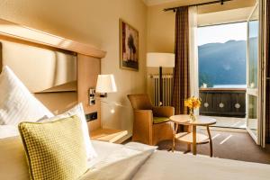 a hotel room with a bed and a chair and a window at Eibsee Hotel in Grainau