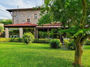 a house with a green yard with a tree at Posada el Remanso de Trivieco in La Cavada