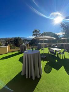a patio with tables and umbrellas on the grass at Hotel Escuela Santa Brígida in Santa Brígida