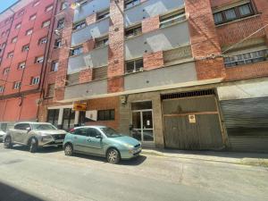two cars parked on a street in front of a building at Apartamento Enol in Cangas de Onís